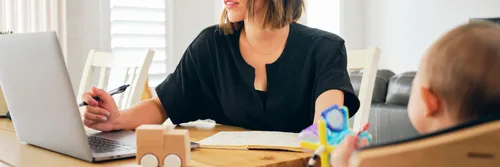 A young woman balances working at home with her family life, on a web conference while attending to her baby