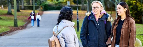 Three females in conversation outside the University
